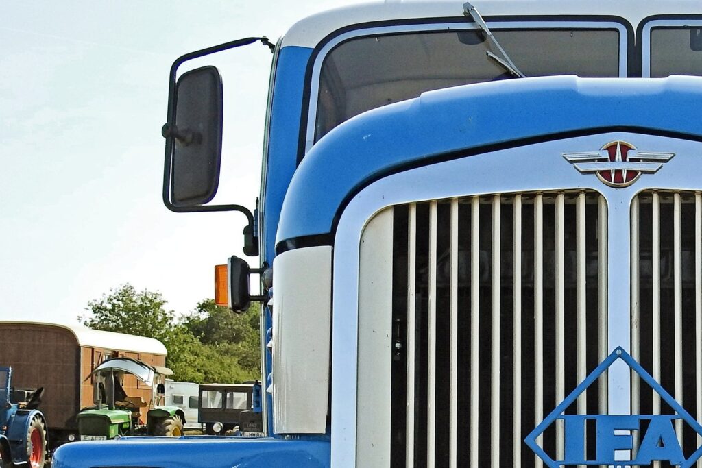 Grill of a blue big rig focused on the large mirror.