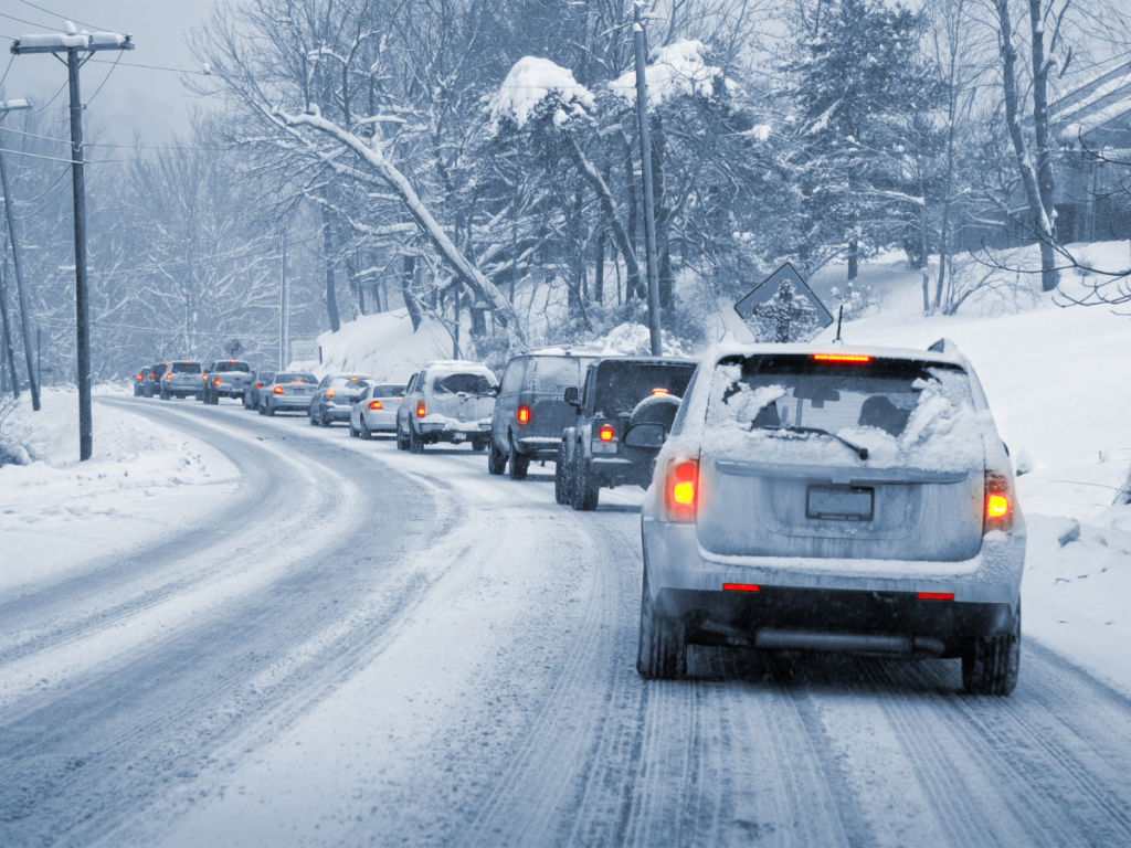 A snowy road with lots of cars also coated in snow.