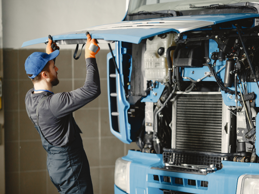 A mechanic looking under the hood of a semi truck.